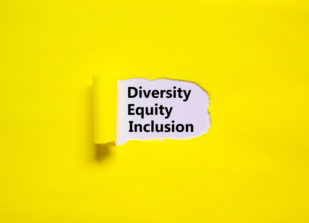 Diversity, equity, inclusion DEI symbol. Words DEI, diversity, equity, inclusion appearing behind torn yellow paper. Pink background. Business, diversity, equity, inclusion concept, copy space.